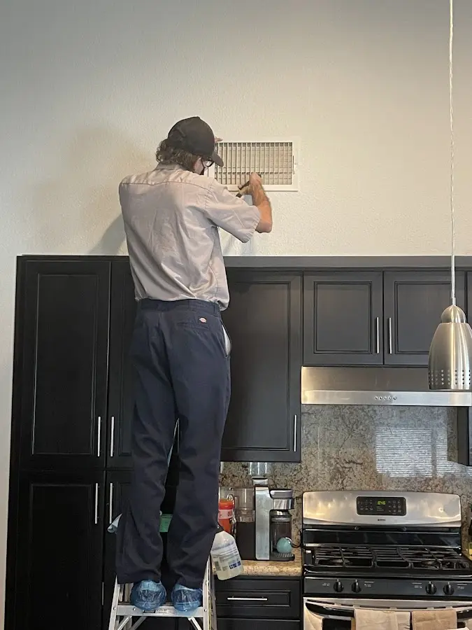 Technician inspecting an air vent during HVAC service in South Jordan